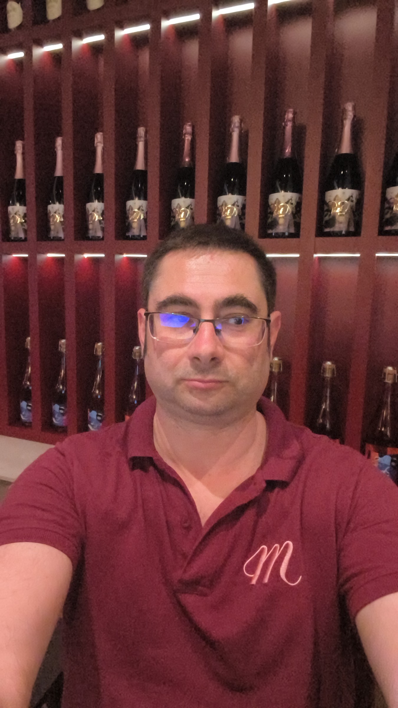 Łukasz at Hotel Muselet — bordeaux polo, champagne wall, the world he inhabits